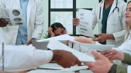 Healthcare professionals experiencing intense workplace stress, throwing medical documents during heated meeting, revealing underlying tension and burnout among diverse medical team