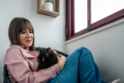 Woman relaxing at home, embracing her black cat in peaceful solitude