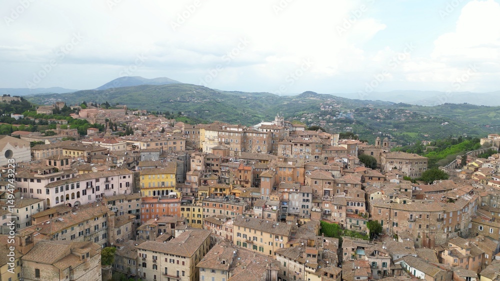 Fototapeta premium Drone aerial view of the historic center of Perugia with the houses perched on the hills of the Umbrian Apennines with the houses with the typical tiled roofs matching each other - Piazza IV Novembre
