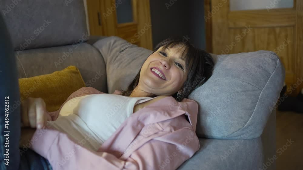 Woman lying on sofa holding paper airplane is smiling and dreaming of future Woman lying on sofa holding paper airplane is smiling and dreaming of future