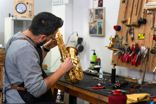 Konstfotografi Instrument repairman examining saxophone in workshop