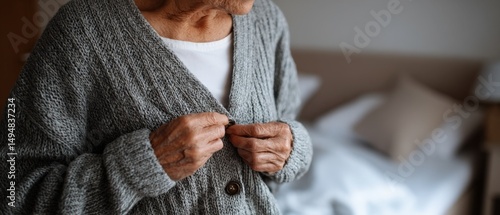 Senior woman buttoning cardigan in bedroom, showcasing aging gracefully and independence in the comfort of her home Concept of elderly care, selfcare, and home living