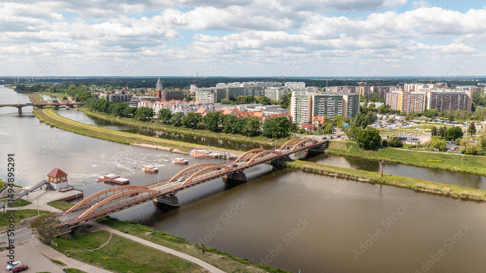 Naklejka premium Aerial panorama of arched traffic bridge over Odra River in Poland with surrounding buildings and urban landscape under cloudy sky