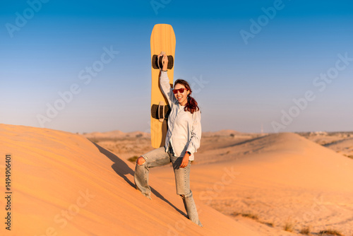 Canvas Print Young woman enjoying the thrill of sandboarding in the sun soaked desert of Duba