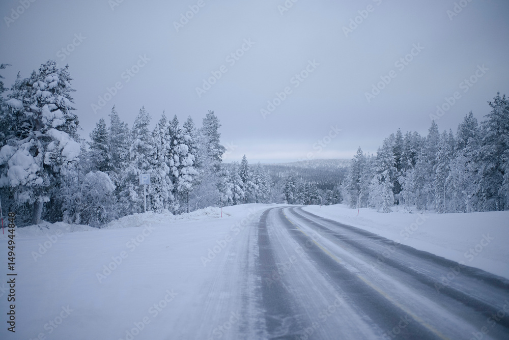 Snow-covered road through a serene winter forest with overcast sky. North Finland Snow-covered road through a serene winter forest with overcast sky. North Finland