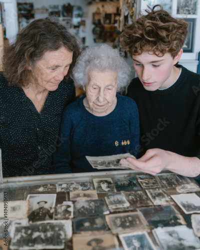 Elderly caucasian women and young caucasian male viewing vintage photographs together