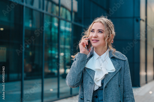 Valokuva Business woman engages in a phone conversation while standing outside a modern o