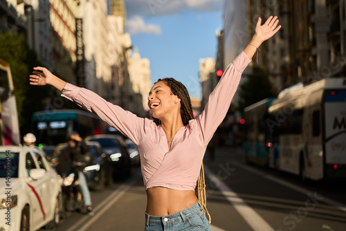 Young latin woman celebrating with open arms in a city street