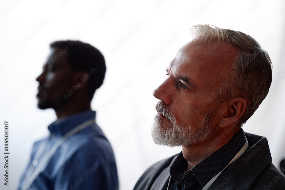 Side view of thoughtful senior man attending business conference actively listening to speakers presentation on latest AI technology updates in lecture room Side view of thoughtful senior man attending business conference actively listening to speakers presentation on latest AI technology updates in lecture room