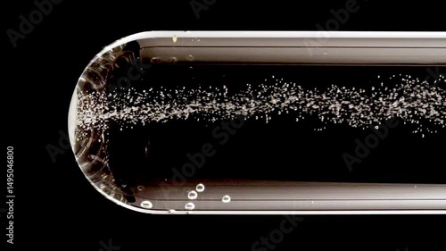 Close up tablet of aspirin, vitamin falls into of water in glass test tube in slow motion on black background. Macro shot of bubbles effervescent. The medicine concept, health care, treatment.FullHD 
