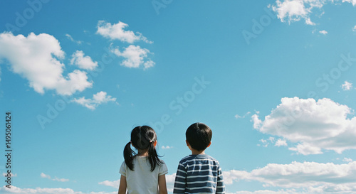 アジア人の子供たちの後ろ姿・青空背景・写真素材