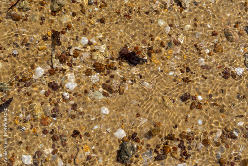 Pattern of light in water flowing over the sand, shells and stones at the water’s edge. Coochiemudlo Island Queensland, Australia