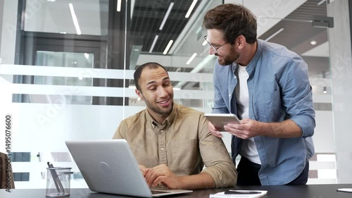 Mature co-worker praises young employee for excellent job at laptop at workplace in business office. Manager motivates colleague worker for job well done. Positive interaction, teamwork, collaboration