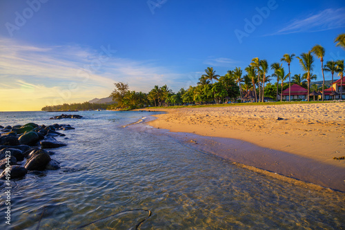 Fototapeta Naklejka Na Ścianę i Meble -  Scenic view of Bel Ombre beach in southern Mauritius with villas, palm trees and sunset light.
