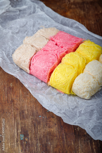 Multicolored pismaniye or pishmaniye also known as cotton candy, dragons beard or candy floss. Light halva, traditional turkish sweets. Dessert on paper