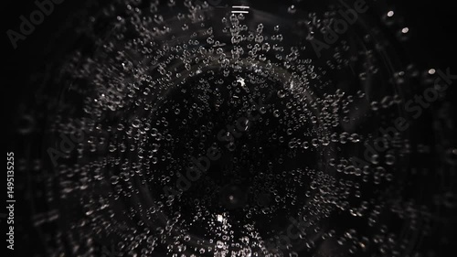 Drinking water with bubbles in a transparent glass macro shot close-up, carbonated drinking water on a black table in a glass. Top view, slow motion