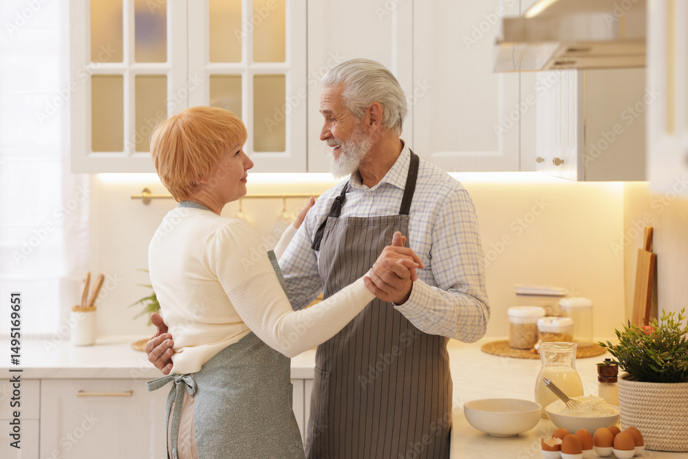 Fototapeta premium Senior couple dancing while cooking in kitchen