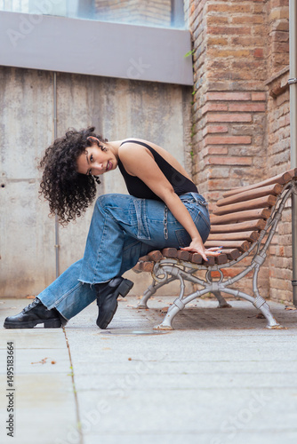 African American woman dancing in a creative pose between benches in an urban setting. he wears casual clothes and shows balance,strength, and expression. Concept of movement, art,and freedom.Vertical