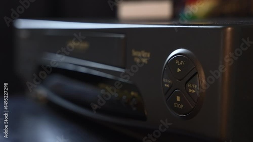 Hand inserting VHS tape into vintage VCR and pressing play