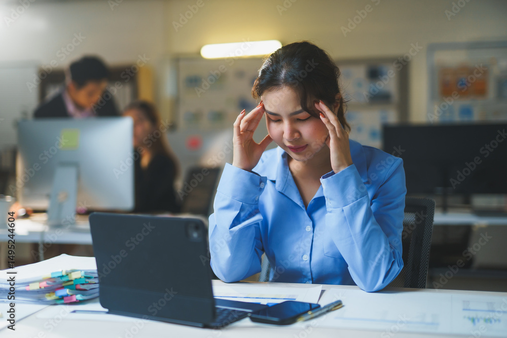 Young office worker experiencing a headache and stress while managing tasks at the workplace, feeling overwhelmed and fatigued Young office worker experiencing a headache and stress while managing tasks at the workplace, feeling overwhelmed and fatigued