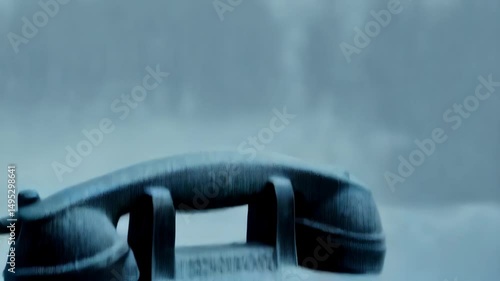 Vintage black rotary dial telephone covered in fresh snow, set against a winter landscape with cold atmosphere and a nostalgic aesthetic.
