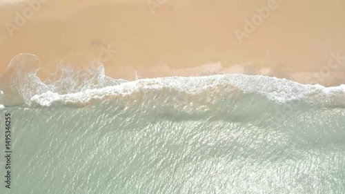 Relaxing ocean waves gently flow on a sandy beach at sunset