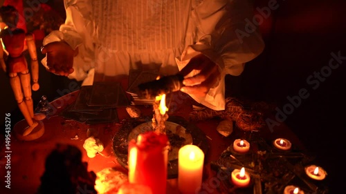 Mystical ritual with burning candles, tarot cards, and a person s hands performing a spiritual ceremony in low light ambiance.