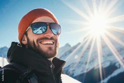 Bright winter day in the mountains with a smiling man wearing sunglasses and a beanie enjoying the sun and snow on a scenic hiking adventure