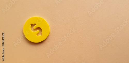 yellow coin with dollar sign and beige background conceptual photo