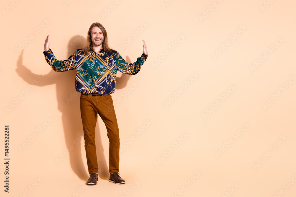 Obraz premium Portrait of a stylish young man posing with cheerful demeanor and a vibrant outfit against a beige background for lifestyle imagery.