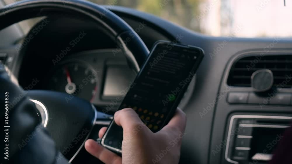 Distracted driver endangering life by texting and reading messages on smartphone while steering car through winding forest road Distracted driver endangering life by texting and reading messages on smartphone while steering car through winding forest road