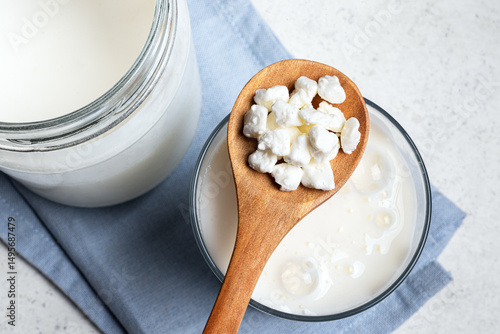 Tableau sur toile Milk kefir grains on wooden spoon and jar of kefir