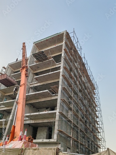 Under construction residential building with Concreate Block structure and Fixed Tower Crane
Exterior view Highrise Multistory Tower modern design
Yellow Tower Crane and erected Scaffolding Around it.