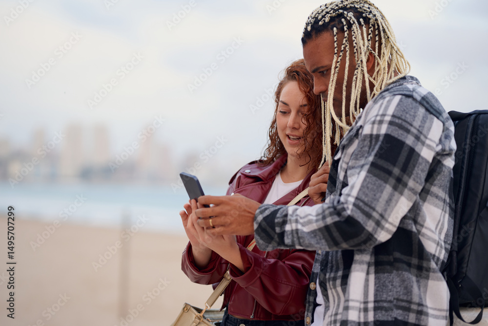 Fototapeta premium Friends sharing exciting moments on a beach with a smartphone