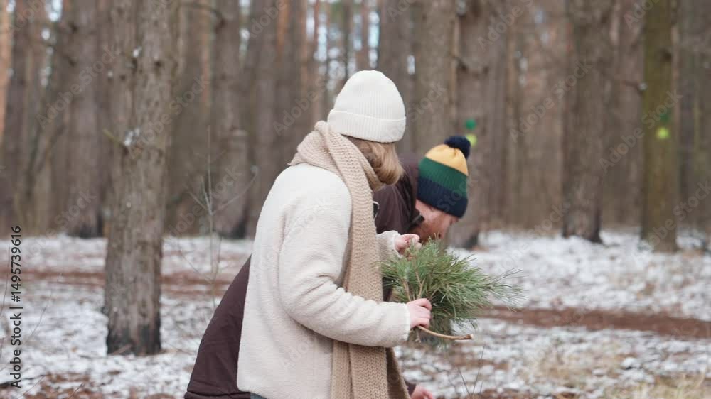 custom made wallpaper toronto digitalAn adult White woman is holding some pine branches, an adult White man with a red beard is picking something up from the ground, and their school-age son is walking beside them in a snowy forest area.
