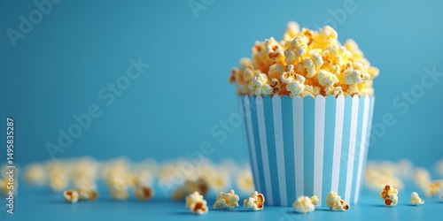 Freshly popped popcorn fills a striped container against a bright blue background creating a playful and inviting atmosphere