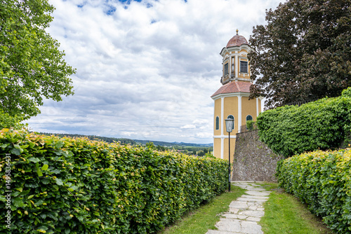 Old Stone Path Leading to a Spiritual Retreat. A well-worn stone path guides visitors toward an ancient church tower, a peaceful haven in nature’s embrace