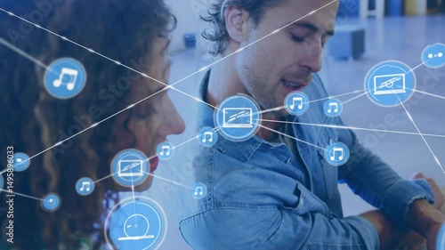 Office colleagues typing on laptop and animating tech network overlay with icons for collaboration