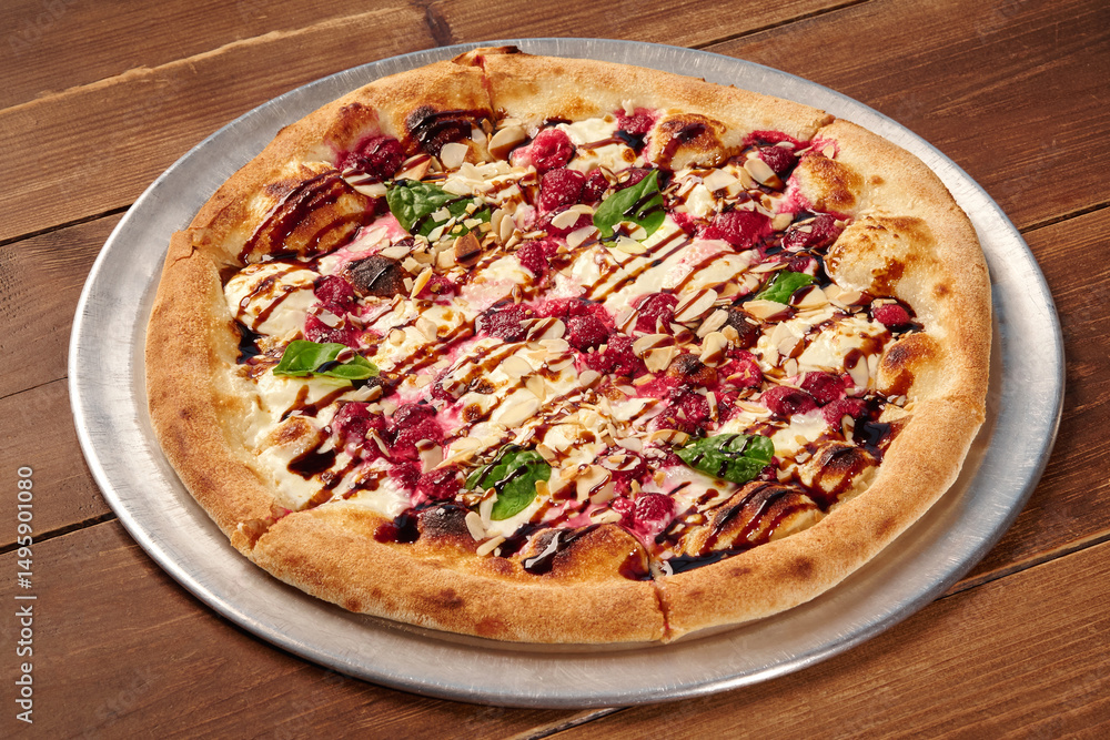 Delicious gourmet pizza with raspberries, almonds, balsamic glaze and basil on wooden table Delicious gourmet pizza with raspberries, almonds, balsamic glaze and basil on wooden table