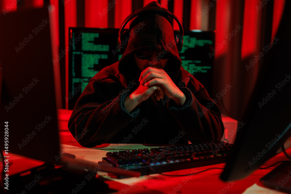 Obraz premium Lone hacker in a dark glowing room hacking data for cyber theft, symbolizing digital crime and online security threats.