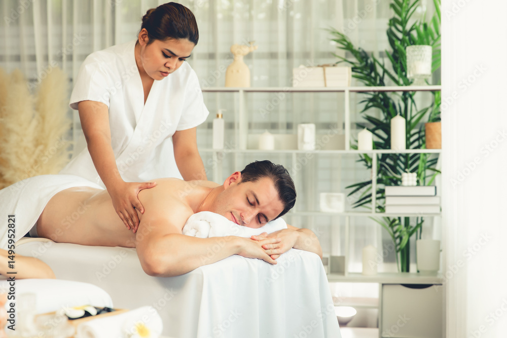 Obraz premium Caucasian couple customer enjoying relaxing anti-stress spa massage and pampering with beauty skin recreation leisure in day light ambient salon spa at luxury resort or hotel. Quiescent