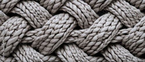 A close-up image of a knitted fabric with a complex interwoven pattern.