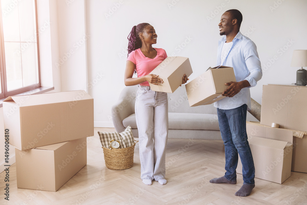 Happy African American couple carrying cardboard boxes moving in new home Happy African American couple carrying cardboard boxes moving in new home