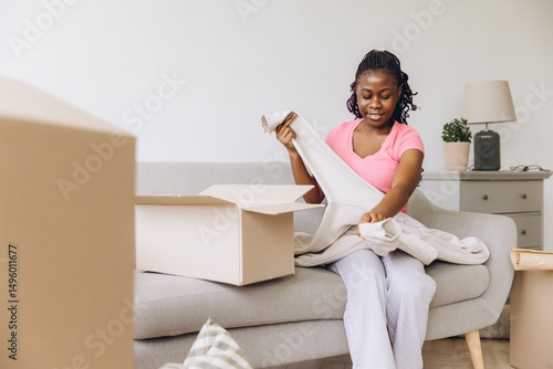 Young African American Woman Unpacking Clothes in New Apartment After Moving In