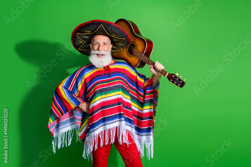 Mature man in colorful traditional outfit holding guitar in lively pose against vibrant green background