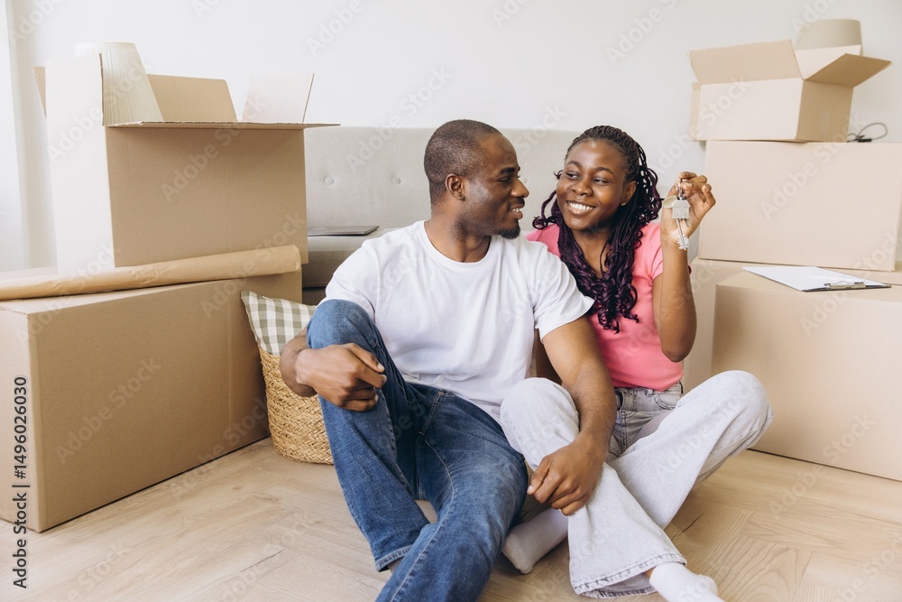 Happy african american couple moving in new house showing keys Happy african american couple moving in new house showing keys