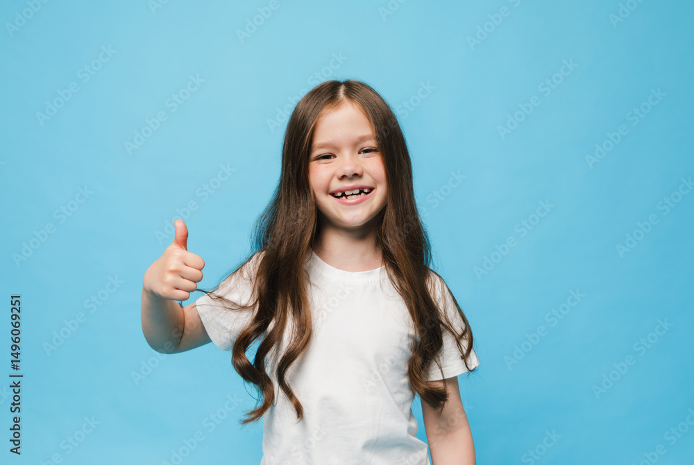 happy little brunette girl standing on blue background showing thumb up happy little brunette girl standing on blue background showing thumb up
