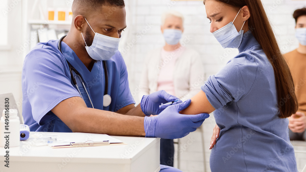 Obraz premium Covid-19 Vaccination. Pregnant Lady In Medical Mask Receiving Coronavirus Vaccine Injection In Hospital. Covid 19 Immunization, Cure And Medicine Treatment Concept. Panorama, Cropped