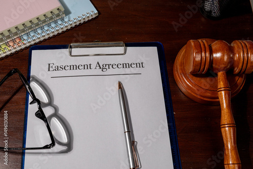 Photos A legal easement agreement rests beside a judge’s gavel on a wooden desk, symbolizing land rights, property access, and legal boundary arrangements
