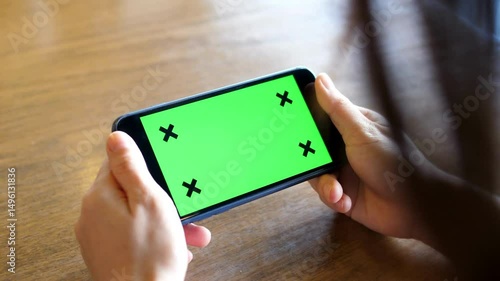 Person Using Digital Smart Phone in Landscape Mode Green Screen Background, Chroma Key mockup handphone content gaming and watching videos